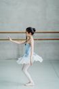 Full body side view of ballerina in tutu and pointe rehearsing dance in ballet studio