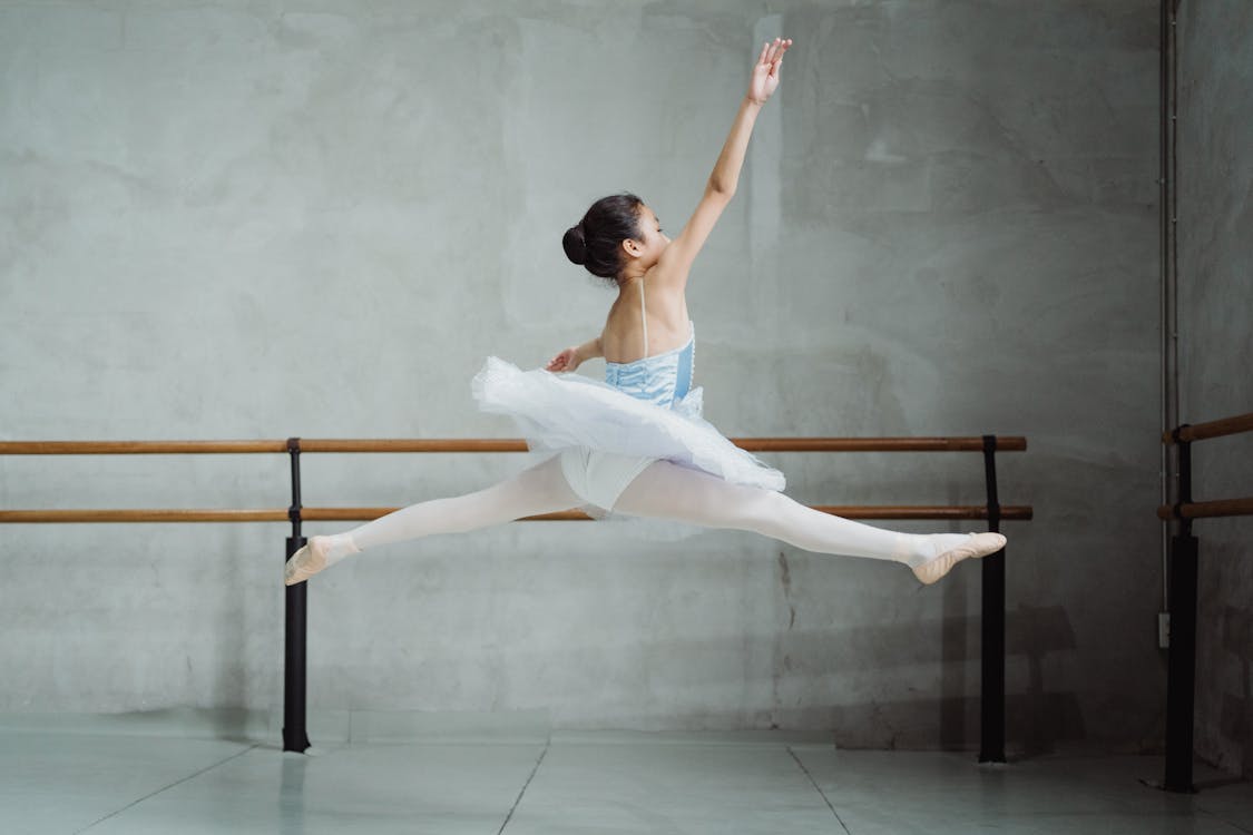 Free Graceful ballerina doing twine jump in studio Stock Photo