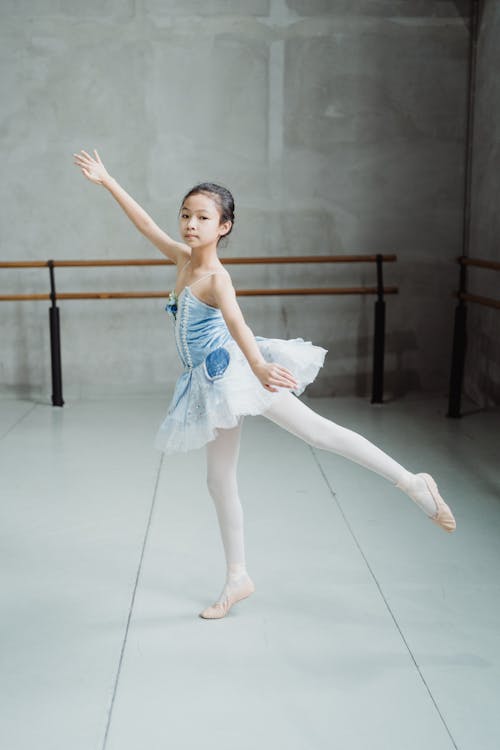 Full body side view of flexible ethnic ballet artist dancing on tiptoe in studio