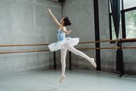 Full body of graceful ballet artist jumping above ground while dancing in choreography hall