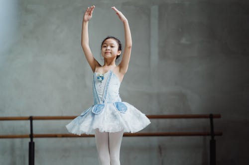 Graceful ethnic little ballerina dancing in studio
