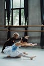 Graceful Asian girl practicing ballet with ballerina in studio