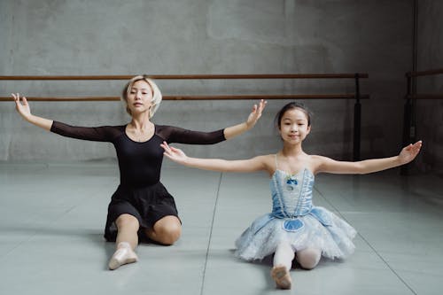 Ragazza Graziosa Asiatica Che Fa Mossa Di Balletto Con L'istruttore