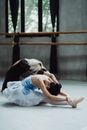 Graceful woman with pupil doing stretch exercise in ballet studio