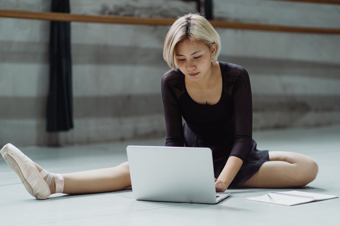 Concentrated Asian ballerina typing on netbook