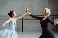 舞蹈室里，一位年轻的亚洲女芭蕾舞演员正与老师一起优雅地练习