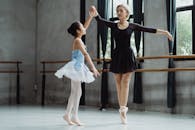 Ballerina with teacher dancing in studio