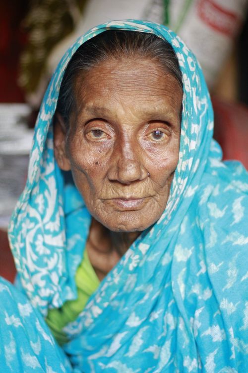Free Close-up portrait of an elderly woman with a blue headscarf, showcasing wrinkles and wisdom. Stock Photo