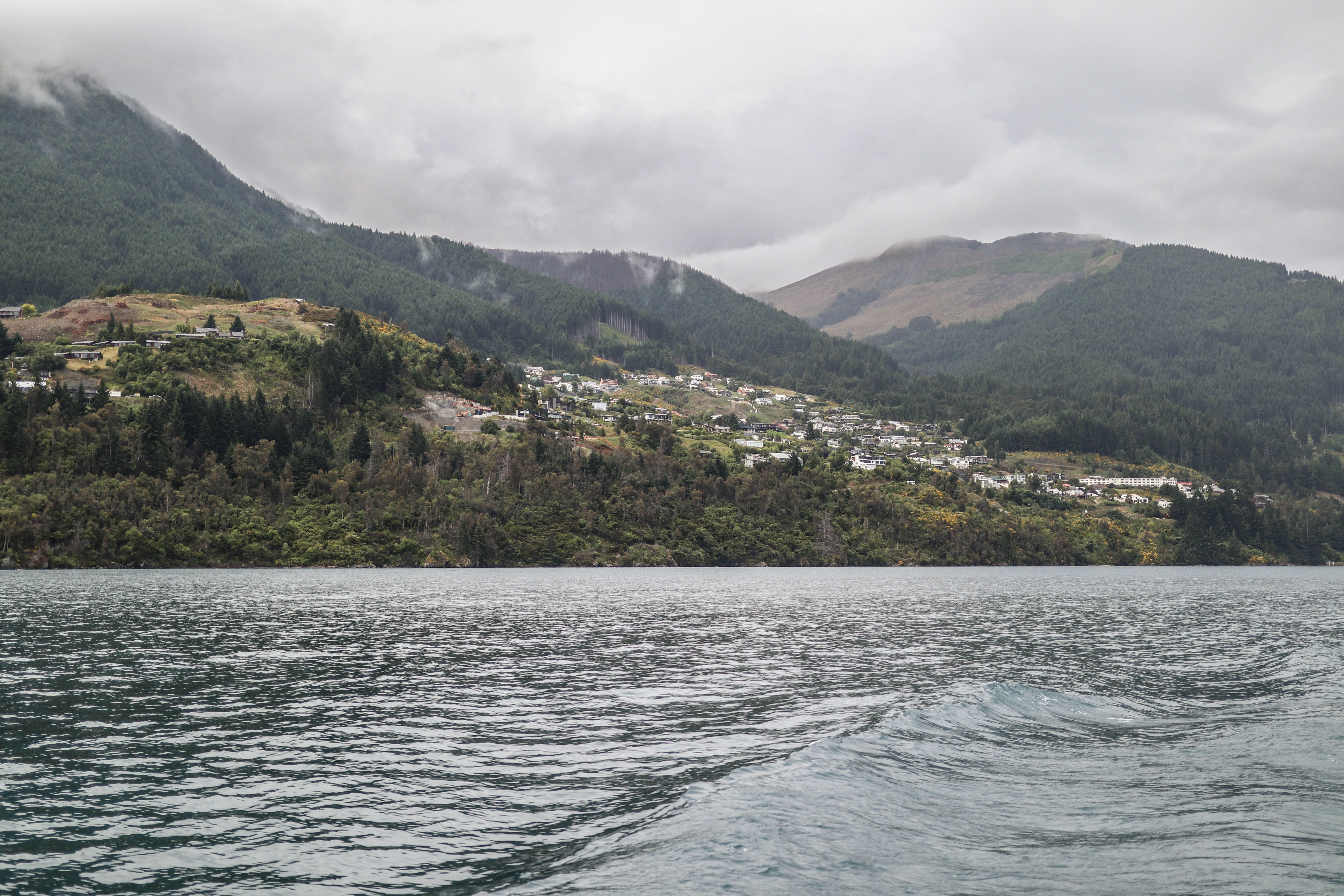 Best Franz Josef Glacier Helihike ex Queenstown Review: The Ultimate New Zealand Adventure Review 2026 - Dramatic landscape of Queenstown's lake surrounded by lush green mountains under a cloudy sky.
