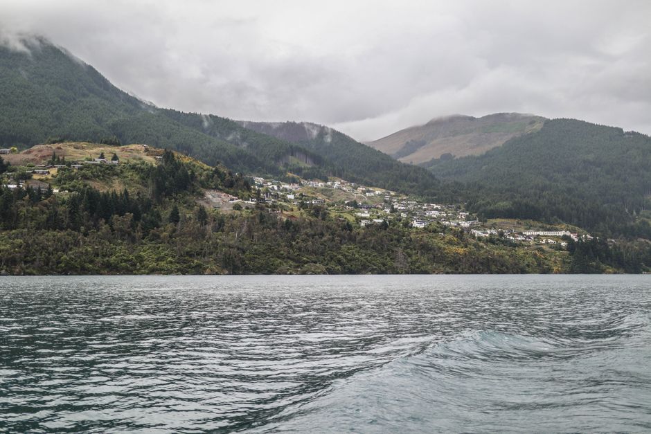 Best Franz Josef Glacier Helihike ex Queenstown Review: The Ultimate New Zealand Adventure Review 2026 - Dramatic landscape of Queenstown's lake surrounded by lush green mountains under a cloudy sky.