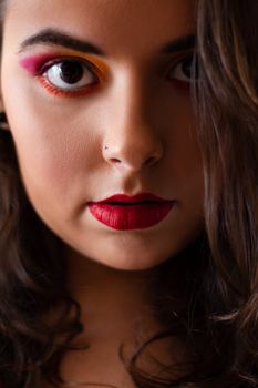 Vibrant close-up portrait of a woman with colorful eye makeup and red lips.