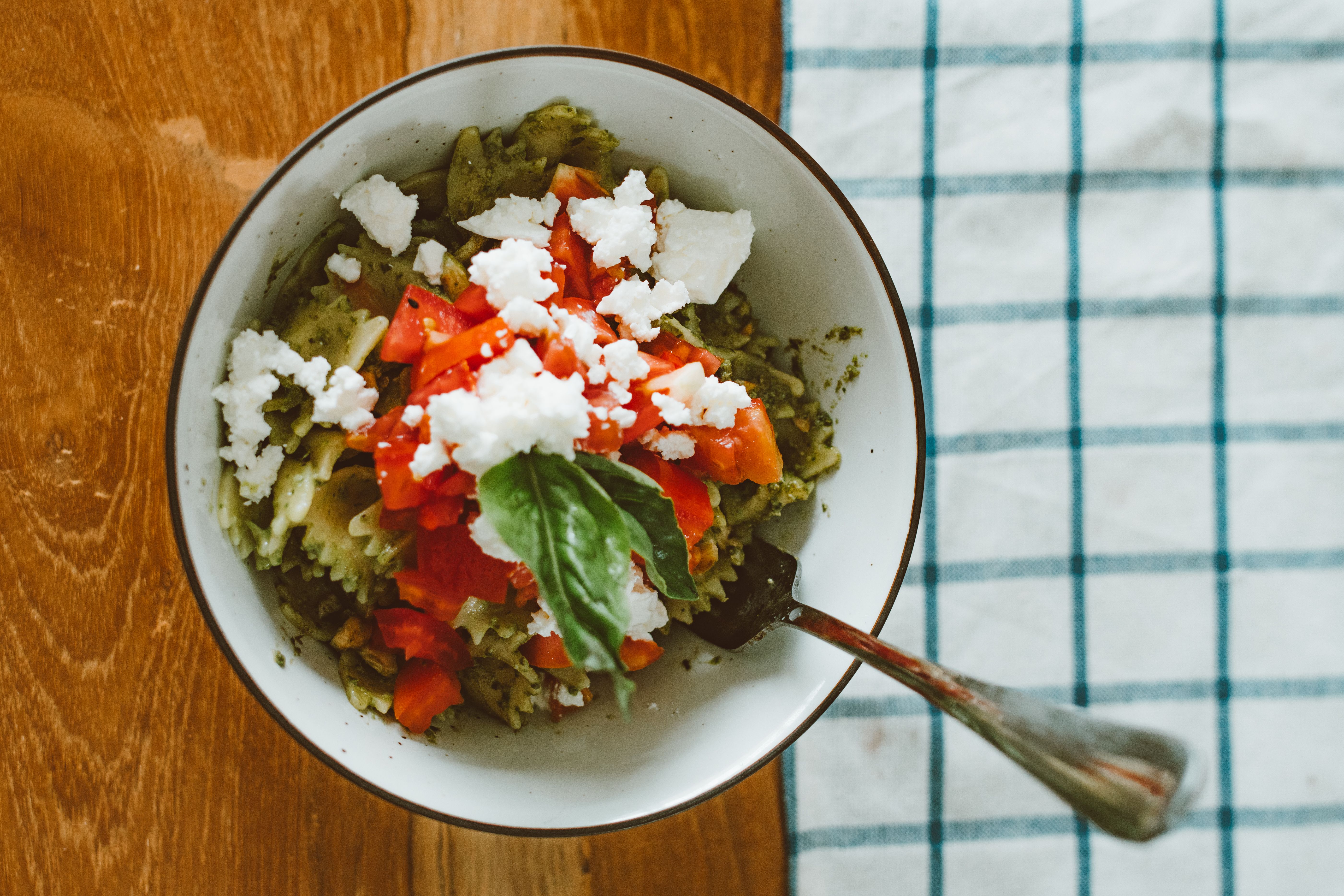 Close-up of creamy baked feta pasta with roasted tomatoes and basil on a wooden table