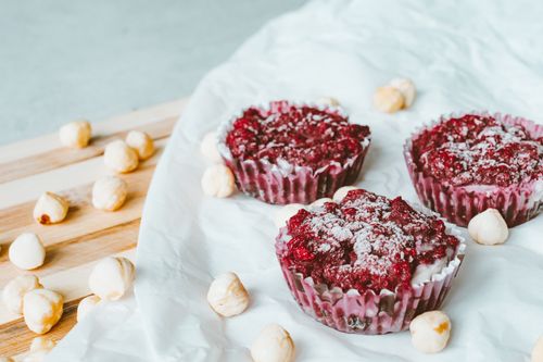 Free Tantalizing raspberry muffins dusted with sugar, surrounded by hazelnuts on parchment. Stock Photo