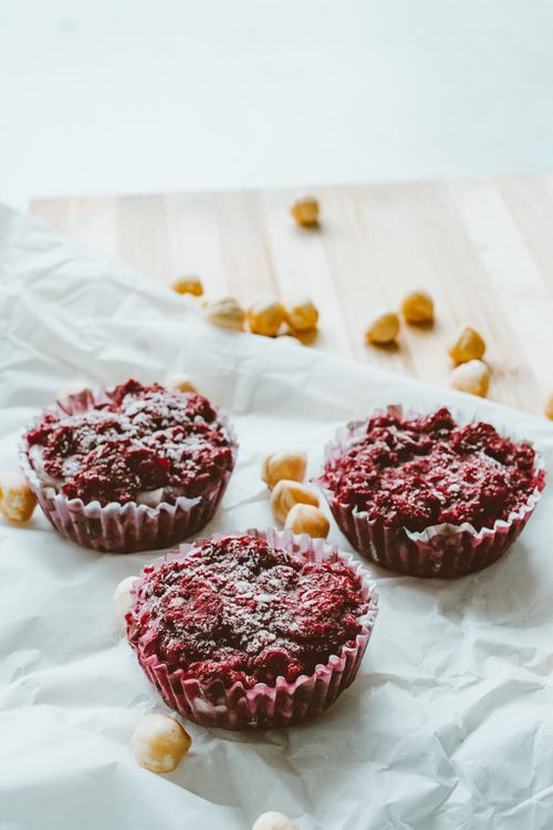 Free Tasty homemade berry muffins garnished with powdered sugar and hazelnuts on a rustic surface. Stock Photo