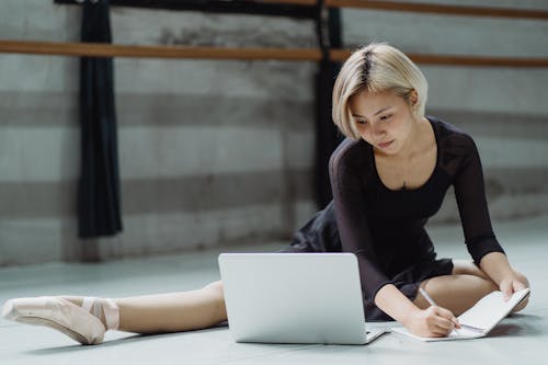 Busy ethnic woman using laptop in dance hall