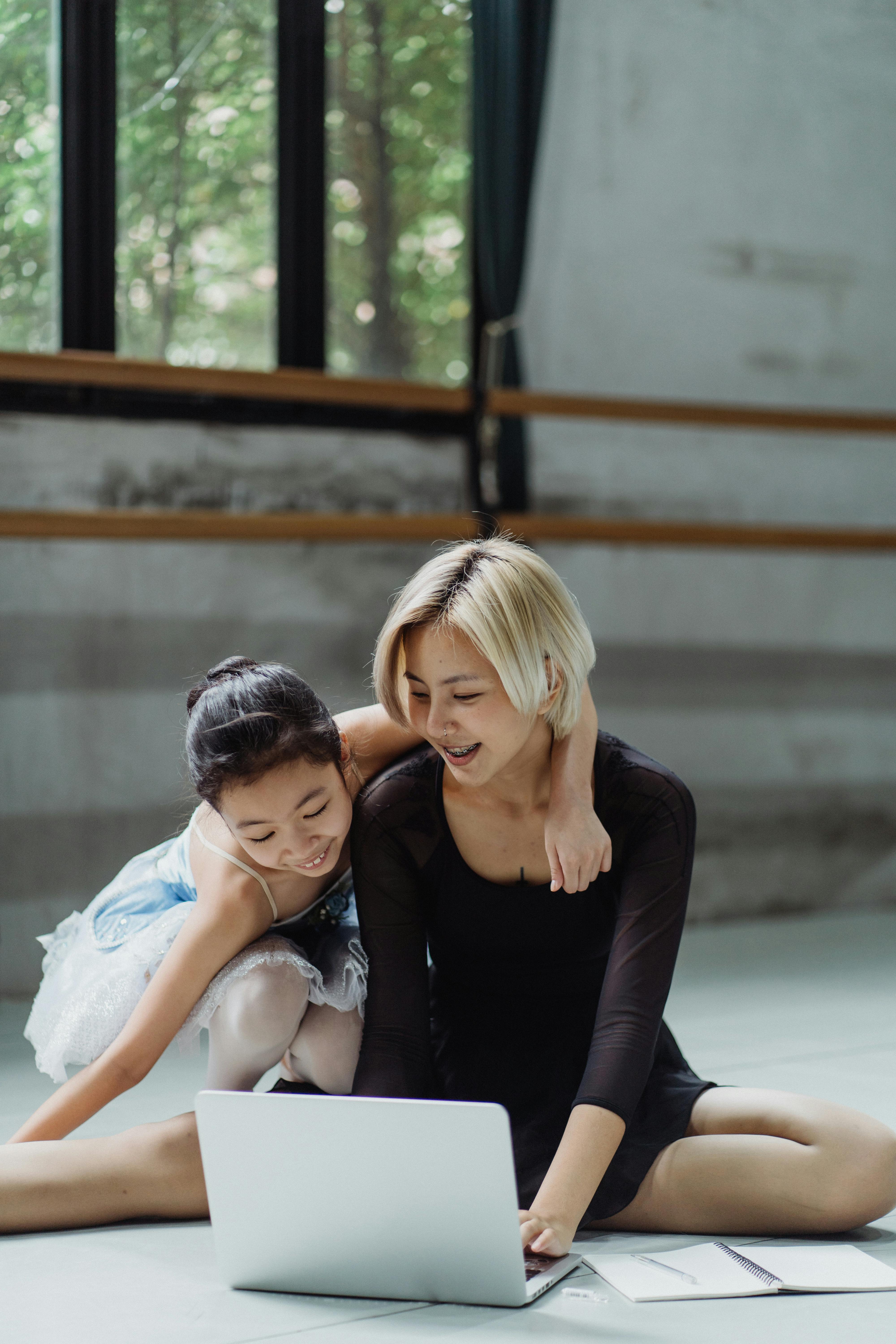 joyful asian girl and dance instructor surfing laptop