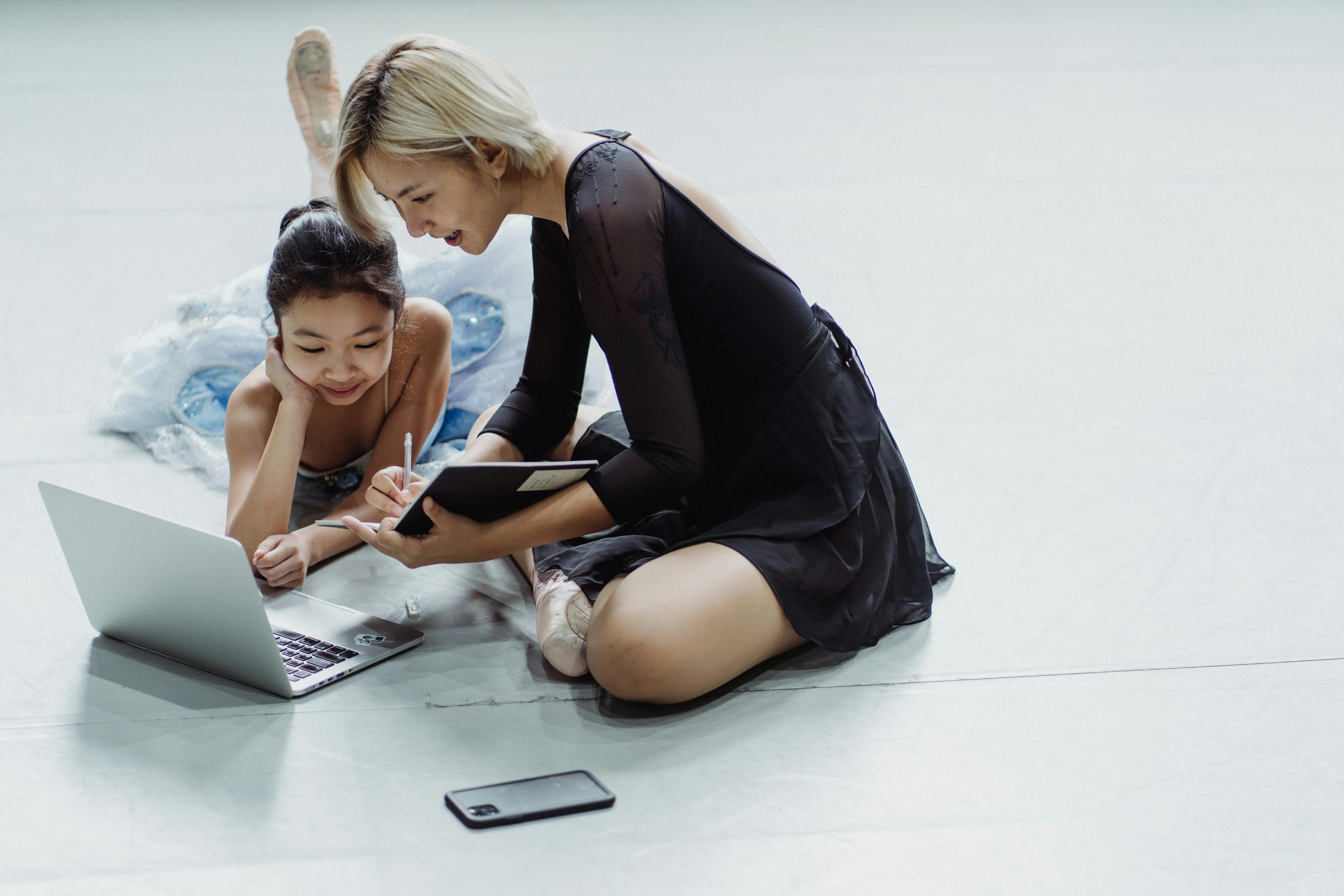 cheerful asian girl and woman using laptop in choreography hall