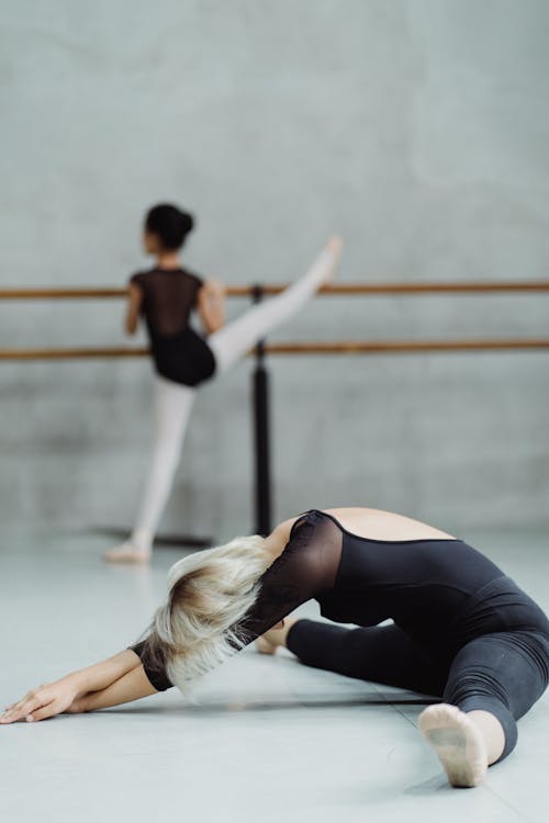 Flexible Frau, Die Auf Boden Mit Mädchen Auf Barre Streckt