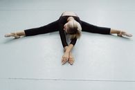Flexible woman stretching body on floor