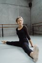 Full body of focused Asian female ballet dancer doing split while leaning on hands on floor