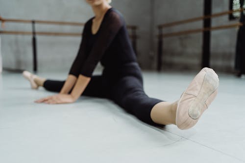 Free Selective focus of crop faceless ballerina in pointe doing split exercise in ballet studio Stock Photo