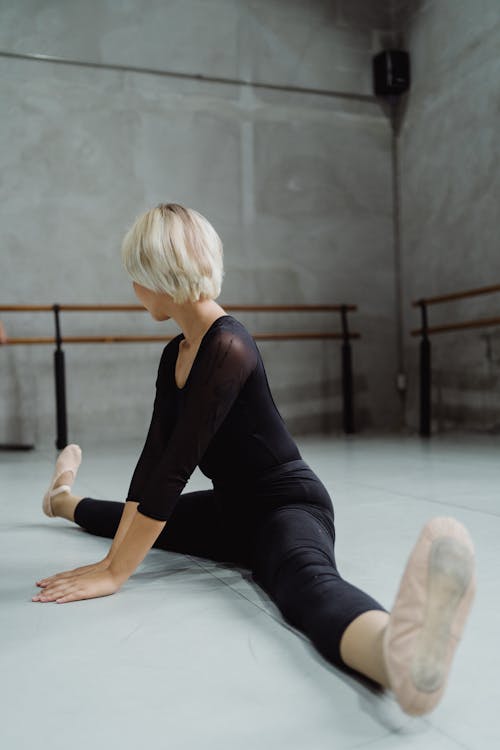 Free Full body of anonymous female ballet dancer stretching body during class in dance studio Stock Photo