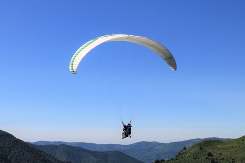 Free Experience the thrill of paragliding high above mountain landscapes under clear blue skies. Stock Photo