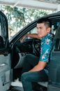 Man in Blue and White Floral Shirt Sitting on Car Seat