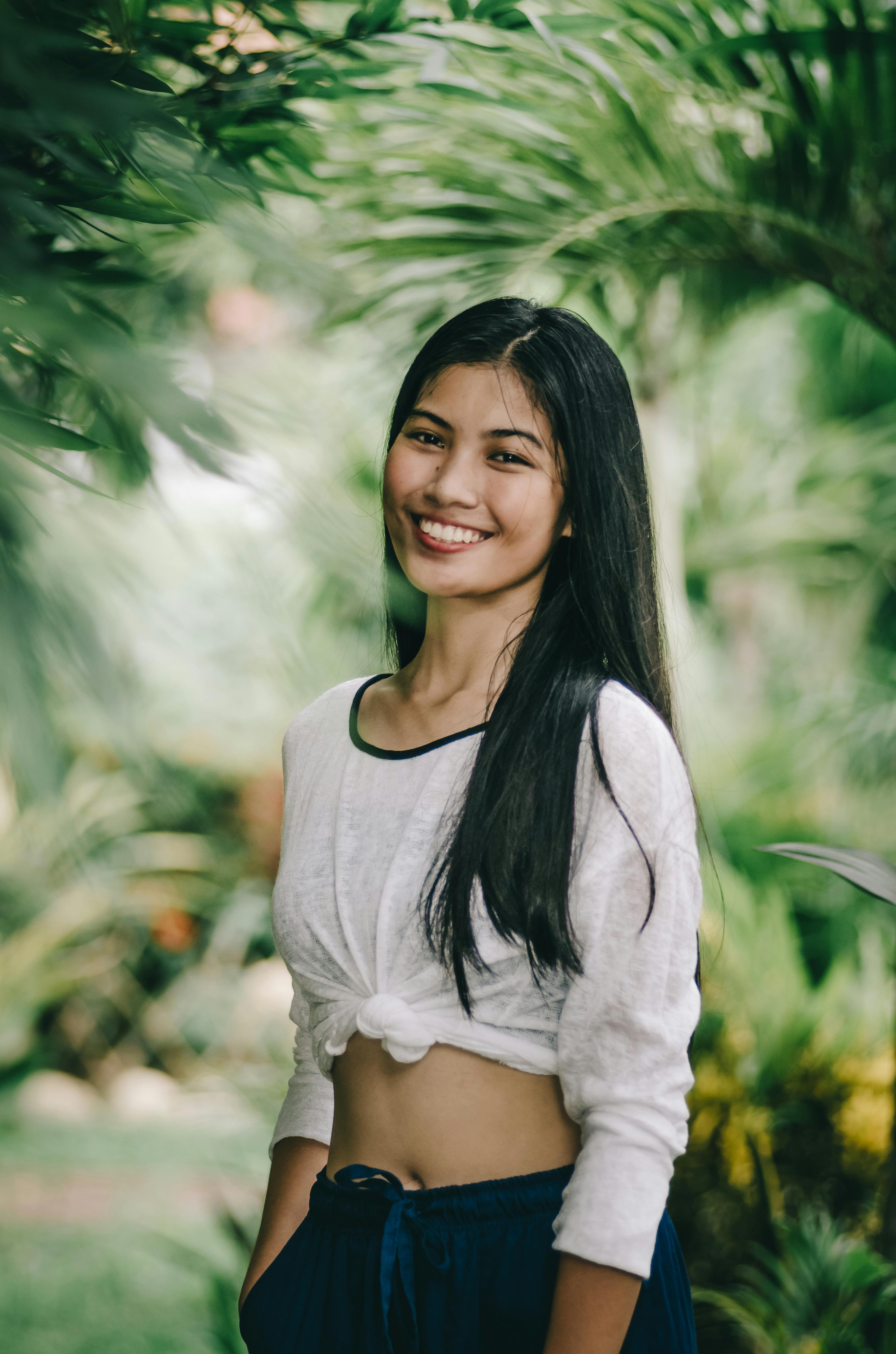 一位年轻女子在郁郁葱葱的热带户外环境中微笑，散发着温暖自然之美