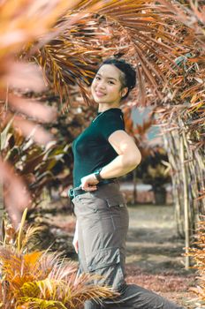 一位年轻女子在阳光明媚、绿树成荫的花园里微笑着快乐地摆姿势