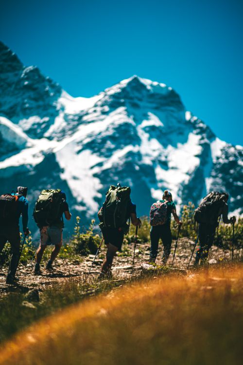 Free A group of hikers trekking on a sunny day by snowy mountains, showcasing adventure and exploration. Stock Photo