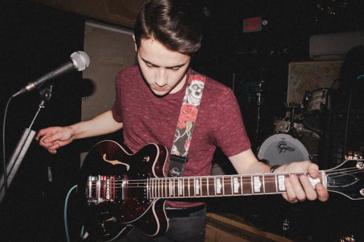 Young male musician performs live, playing electric guitar on stage under spotlight.