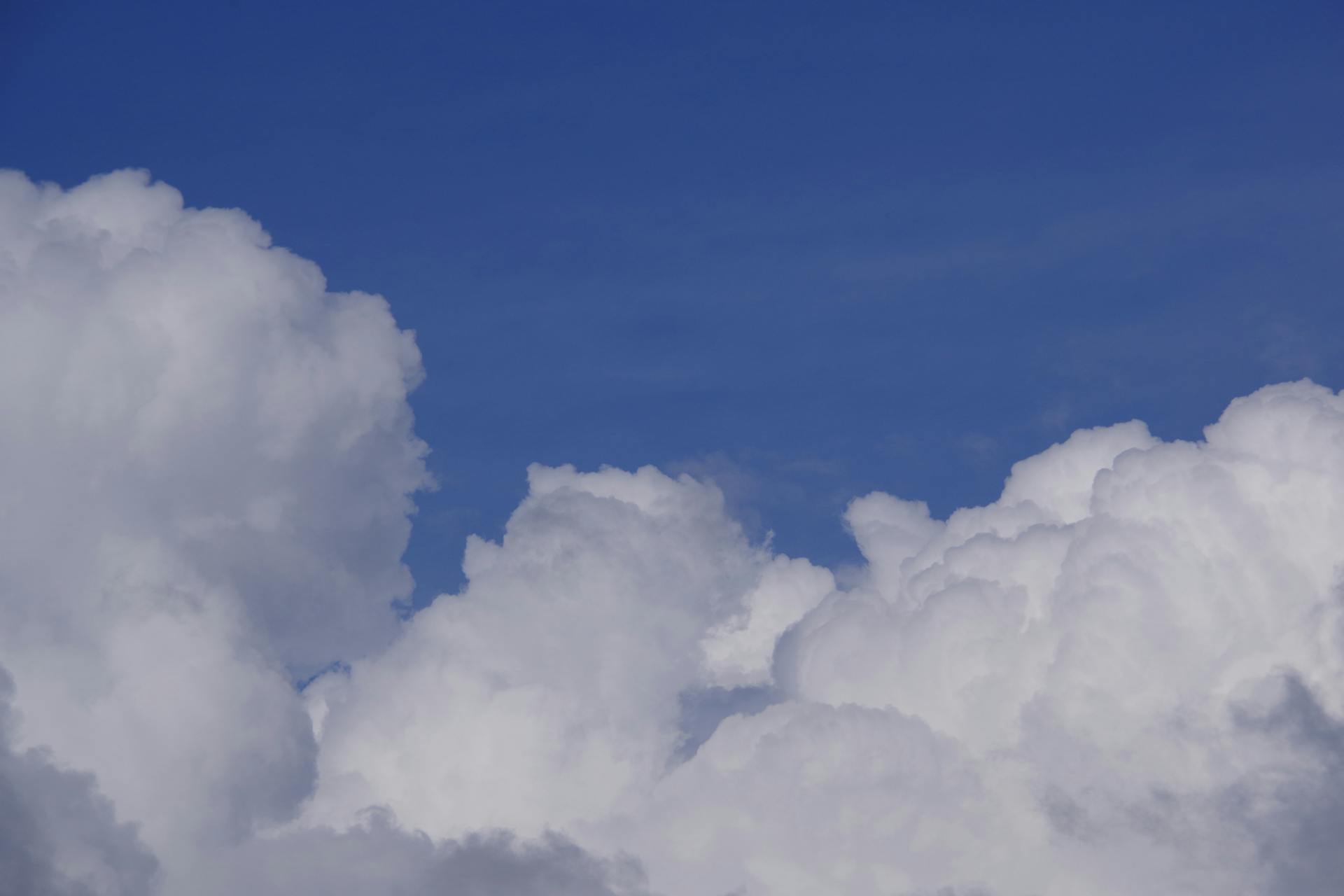 Bright cumulus clouds against a clear blue sky, perfect for backgrounds or wallpaper.