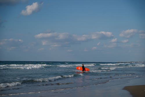 Man Holding a Surfboard Standing on Seashore