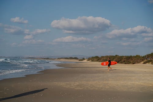 Man Carrying a Surfboard Walking on the Beach