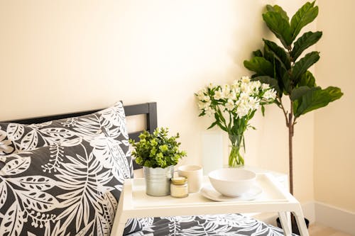 Free Bedroom Interior with Wooden Bed and Flower Vases Beside an Indoor Plant Stock Photo