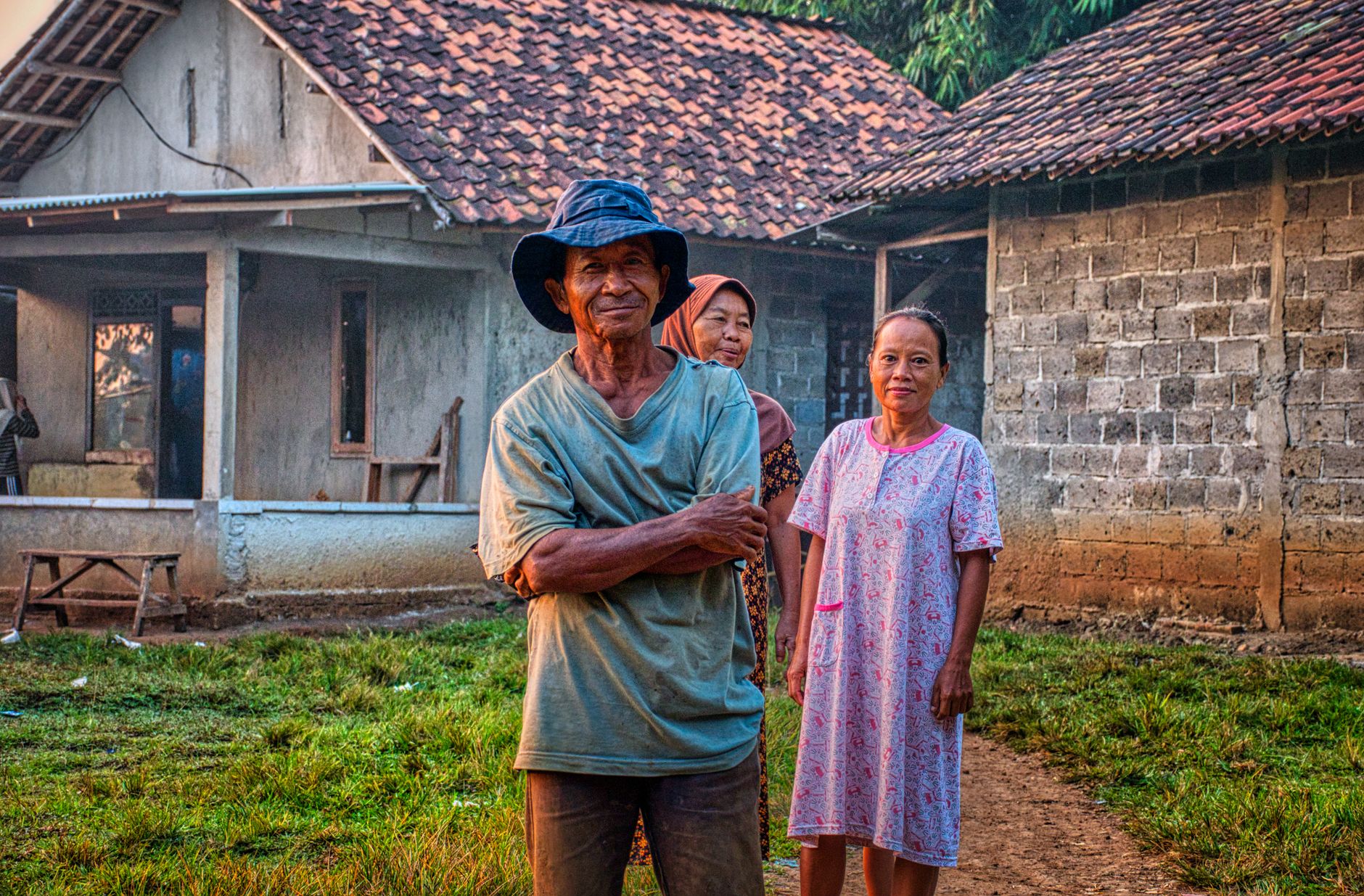 Elderly villagers smiling in front of traditional houses in Rumpin, Indonesia.
