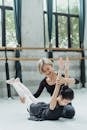 Cheerful Asian ballet teacher stretching back of girl
