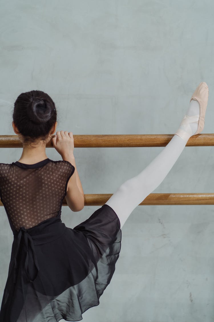 Unrecognizable Girl Stretching Leg On Barre During Ballet Class