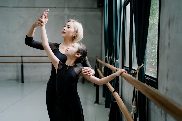 Asian Instructor Teaching Girl During Barre Workout In Hall