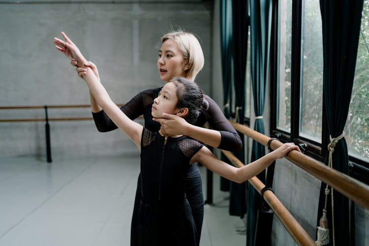 Asian Ballet Teacher Interacting With Pupil During Training In Hall