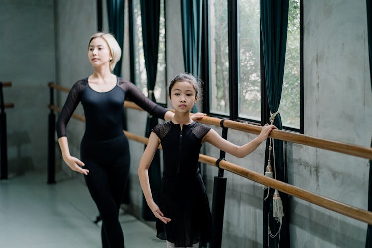 Ballet Teacher With Asian Girl During Barre Workout In Hall