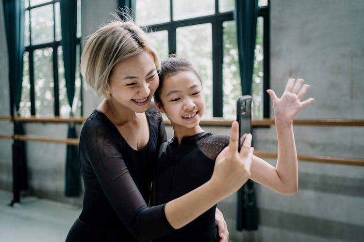 Joyful Asian Ballerinas Taking Selfie On Smartphone In Studio