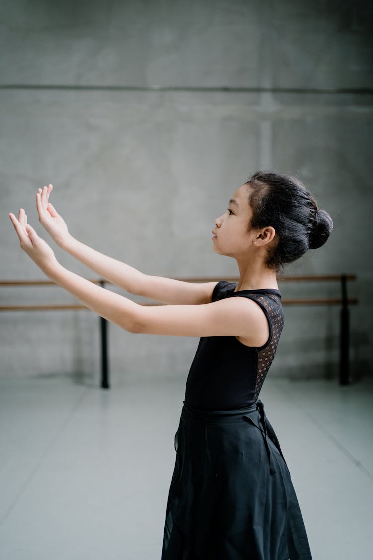 Asian Ballerina Girl Raising Arms Graciously During Ballet Class