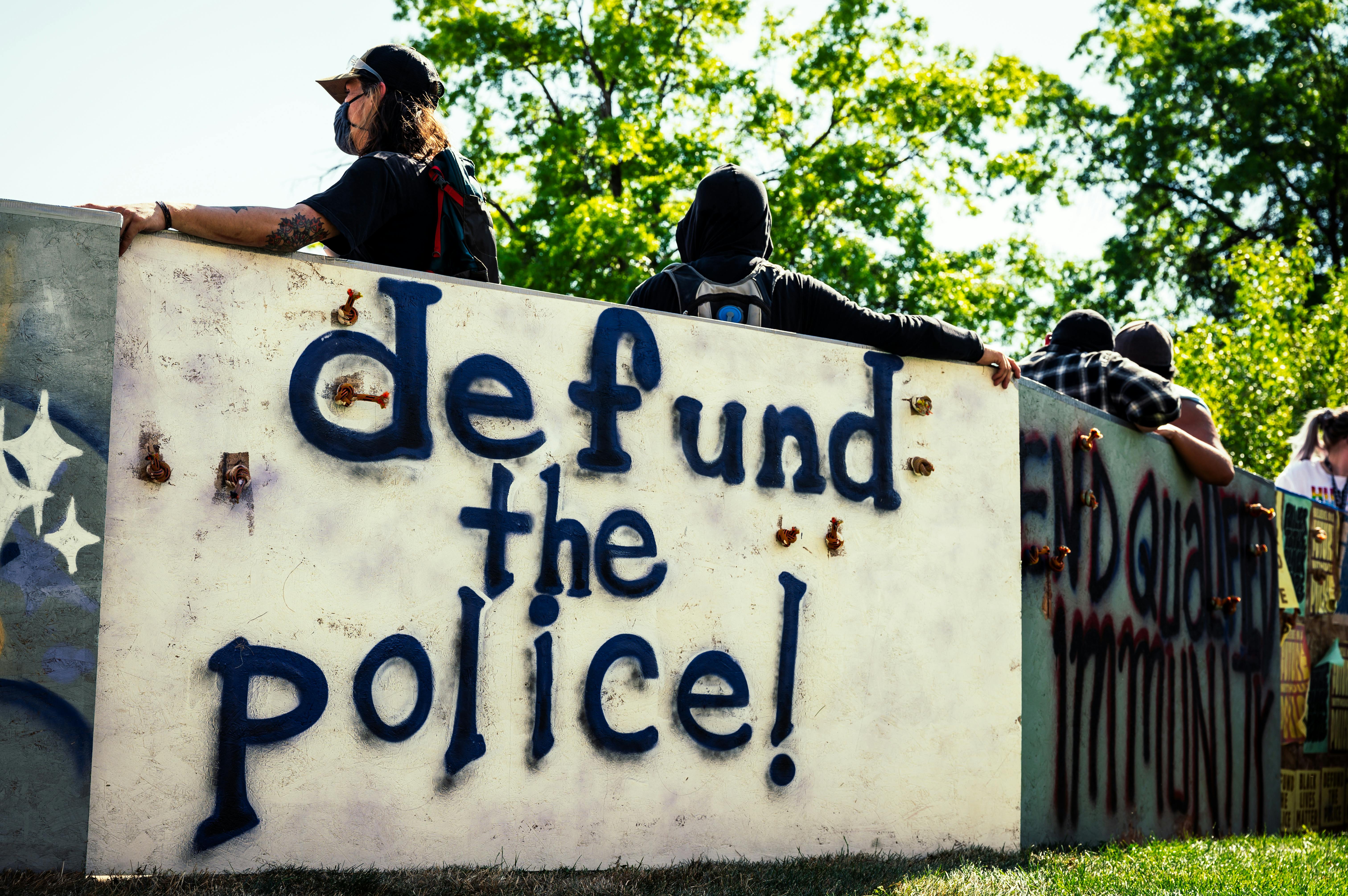 Low angle back view of anonymous activists in face masks standing near wall with graffiti letters during demonstration for equal rights