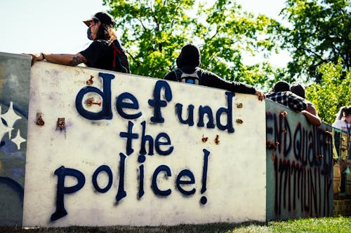Free Low angle back view of anonymous activists in face masks standing near wall with graffiti letters during demonstration for equal rights Stock Photo