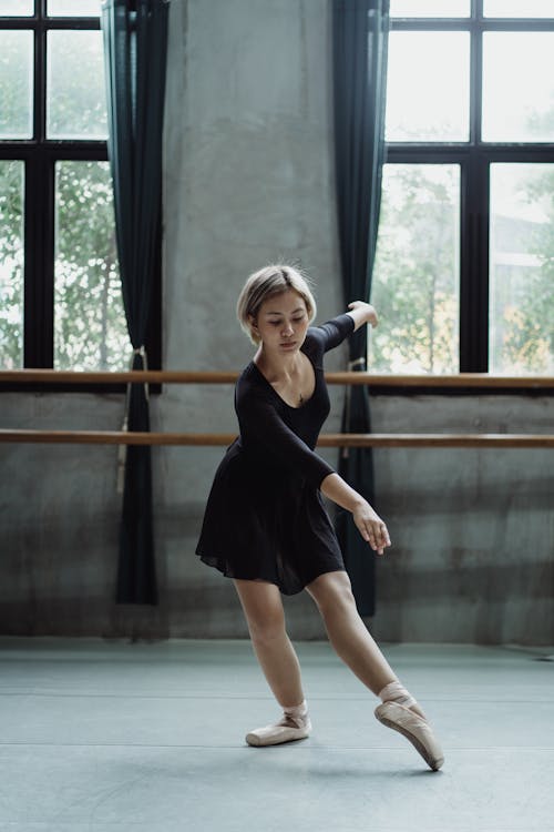 Charming Asian ballerina performing dance in studio