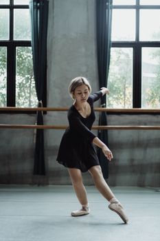 一位熟练的芭蕾舞演员在明亮的大窗户工作室里优雅地跳舞