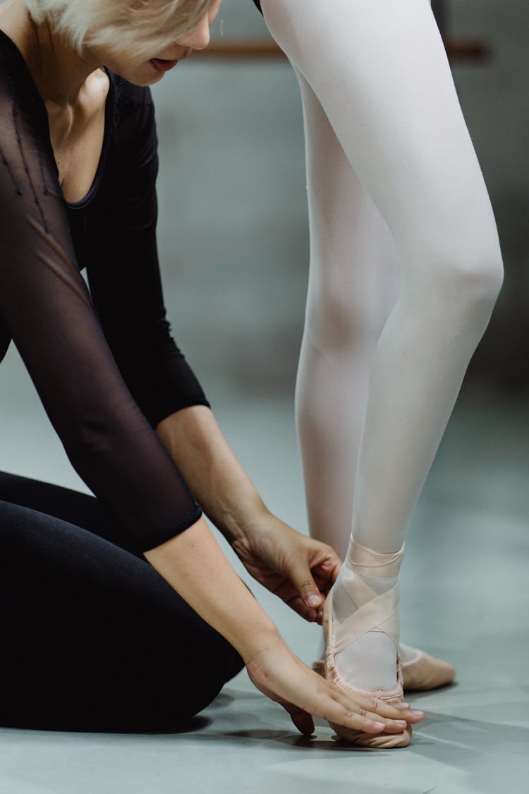 Crop Ballet Instructor Touching Trainees Feet And Explaining Movement Technique