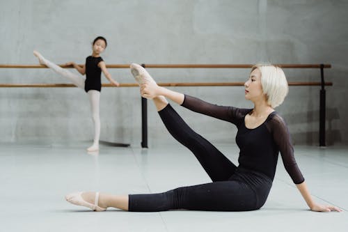 Ethnic girl practicing ballet with tutor in studio
